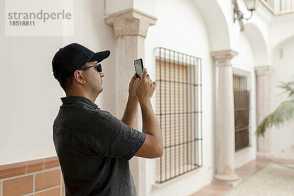 Mann mit Mütze fotografiert mit Smartphone