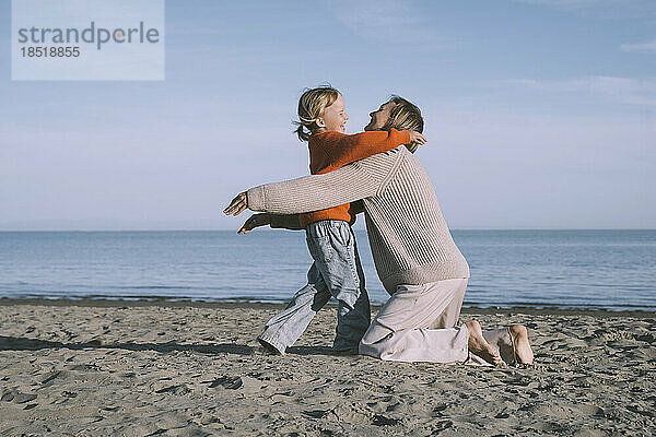 Glückliche Mutter umarmt Tochter am Strand