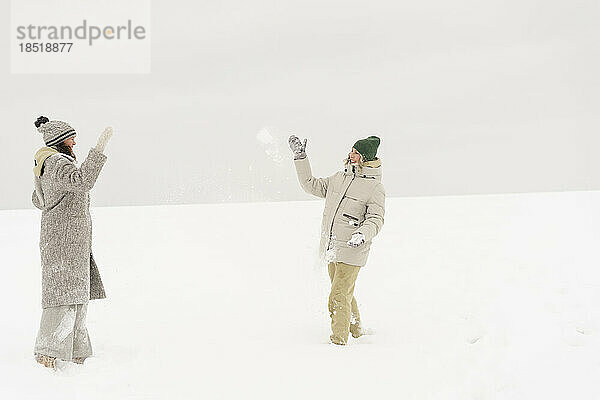 Glückliche Freunde  die im Winter mit Schneeball spielen