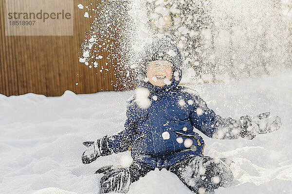 Glücklicher Junge  der im Schnee genießt