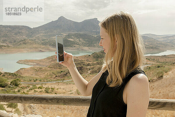 Frau fotografiert an einem sonnigen Tag mit dem Mobiltelefon