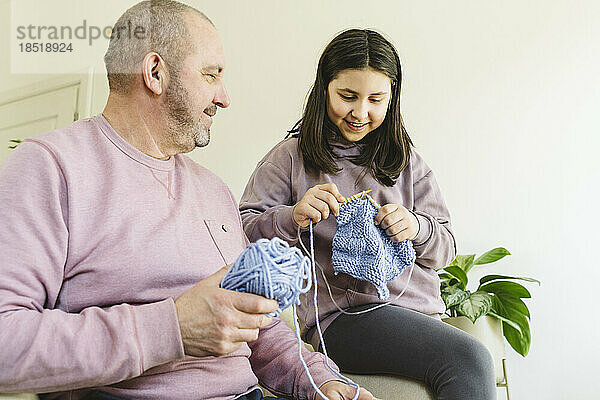 Großvater und Enkelin stricken zu Hause Pullover