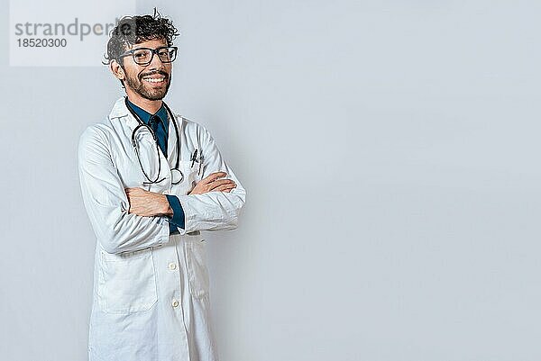 Lächelnder Arzt mit verschränkten Armen auf isoliertem Hintergrund. Lateinischer Arzt mit verschränkten Armen auf isoliertem Hintergrund  Porträt eines jungen Arztes mit verschränkten Armen