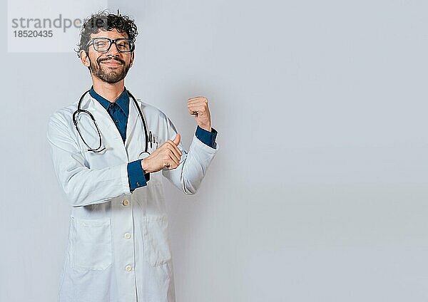 Lächelnder Arzt  der nach hinten zeigt  isoliert. Arzt zeigt mit seinen Daumen zurück  ein Produkt zu empfehlen