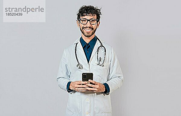 Glücklicher Arzt mit Telefon auf isoliertem Hintergrund. Lächelnde Arzt mit Handy isoliert  Junger Arzt mit Telefon isoliert