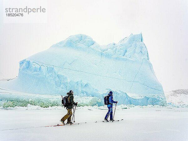 Skitourengeher vor Eisberg im gefrorenen Kong Oscar Fjord  Tasiilaq  Insel Ammassalik  Kommuneqarfik Sermersooq  Ostgrönland  Grönland  Nordamerika
