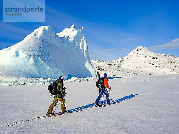 Skibergsteiger vor Eisberg im gefrorenen Kong Oscar Fjord  Tasiilaq  Insel Ammassalik  Kommuneqarfik Sermersooq  Ostgrönland  Grönland  Nordamerika