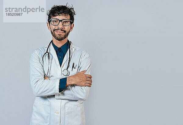 Porträt eines jungen Arztes mit verschränkten Armen. Lächelnder Arzt mit verschränkten Armen auf isoliertem Hintergrund. Lateinischer Arzt mit verschränkten Armen auf isoliertem Hintergrund