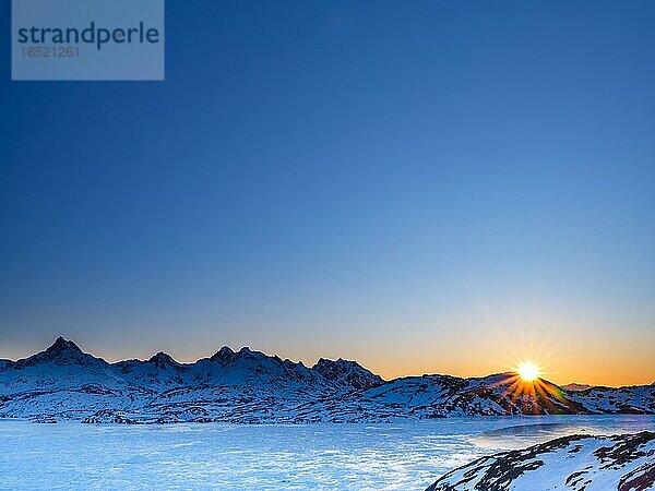 Sonnenaufgang über verschneiten Bergen über dem gefrorenen Kong Oscar Fjord  Tasiilaq  Insel Ammassalik  Kommuneqarfik Sermersooq  Ostgrönland  Grönland  Nordamerika