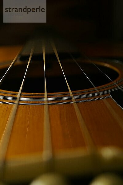 Nahaufnahme der Saiten einer Gitarre vor einem schwarzen Hintergrund