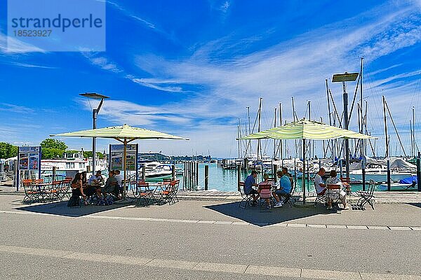 Menschen  die sich an einem sonnigen Sommertag in einem Straßencafé mit Sonnenschirmen im Yachthafen am Bodensee entspannen  Konstanz  Deutschland  Europa
