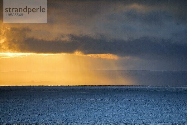Abendsonne bricht durch tiefliegende Regenwolken über den Summer Isles und dem offenen Wasser des blauen Atlantiks  Westküste Schottlands