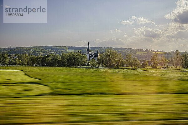 Landschaft in Mitteldeutschland. Blick aus einem fahrenden Zug auf eine Kirche  aufgenommen mit einer langen Verschlusszeit. Bad Hersfeld  11.05.2022  Bad Hersfeld  Deutschland  Europa