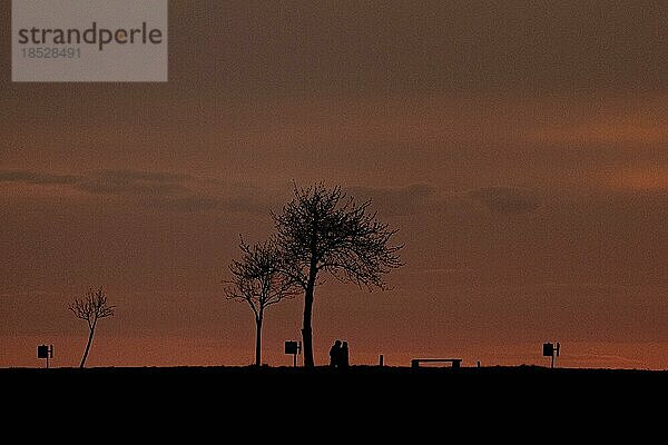 Zwei Spaziergänger zeichnen sich ab als Silhouette vor der untergehenden Sonne  aufgenommen in Gebelzig  13.04.2023.  Gebelzig  Deutschland  Europa