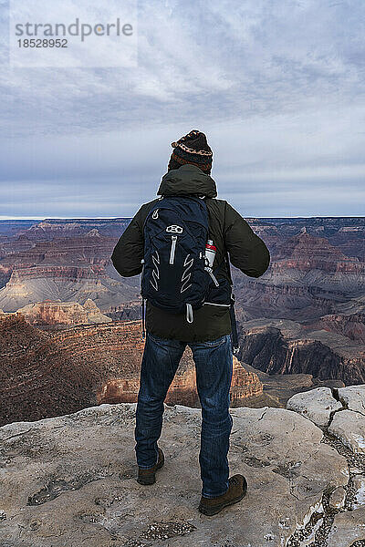 Vereinigte Staaten  Arizona  Grand-Canyon-Nationalpark  Südrand  älterer männlicher Wanderer steht bei Sonnenaufgang am Rande des Grand Canyon