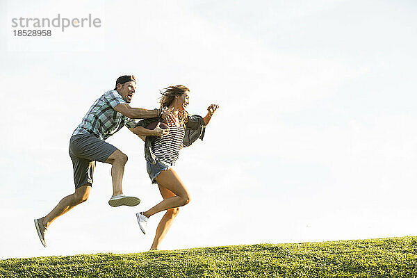 Frau und Mann laufen auf Hügel im Park