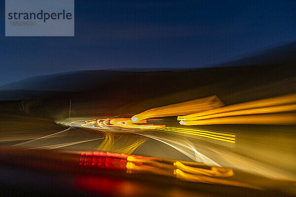 Verschwommenes Bild von Lichtern auf der Autobahn in der Abenddämmerung