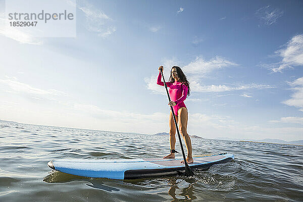 Frau steht auf einem Paddleboard im See