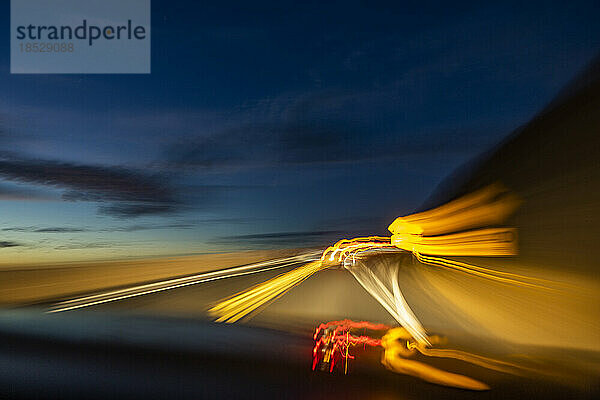 Verschwommenes Bild von Lichtern auf der Autobahn in der Abenddämmerung