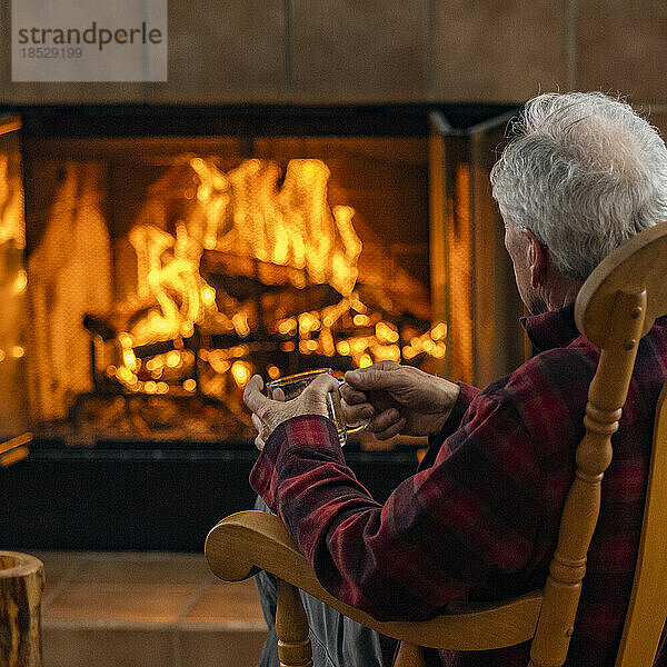 Älterer Mann entspannt sich vor dem Holzkamin