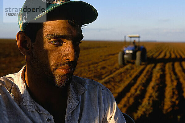 Landwirt auf weitläufigem Ackerland mit seinem Traktor im Hintergrund; Pantanal-Region  Brasilien