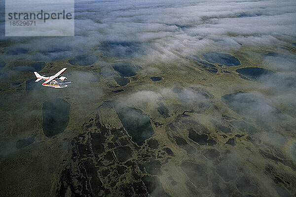 Wasserflugzeug über Wolken und der Tundra von Alaskas North Slope; North Slope  Alaska  Vereinigte Staaten von Amerika
