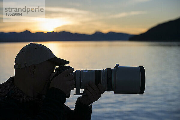 Silhouette eines Fotografen  der ein Foto mit einem langen Objektiv schießt; Inside Passage  Alaska  Vereinigte Staaten von Amerika