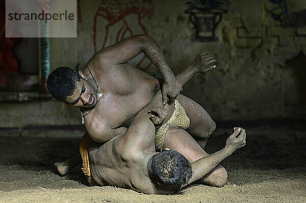 Zwei junge Männer ringen auf einem schmutzigen Boden in Indien; Varanasi  Indien