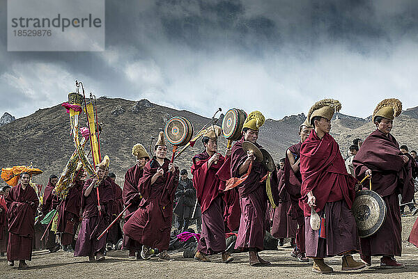 Buddhistische Mönche spielen Musik  während sich Pilger niederwerfen; Langmusi  Amdo  China