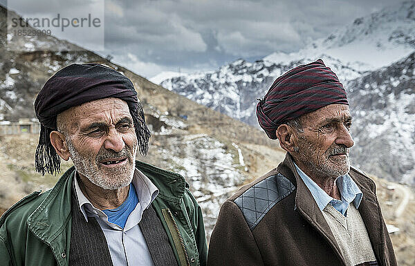 Porträt von zwei kurdischen Männern mit schneebedeckten Bergen im Hintergrund; Urkantakht  Kermanshah  Iran