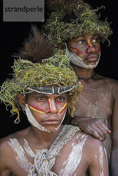 Zwei junge Mitglieder des Huli-Stammes im Tari-Tal im südlichen Hochland von Papua-Neuguinea  die Perücken tragen  die als Teil ihres Übergangs zum Erwachsensein angefertigt wurden; Tigibi  südliches Hochland  Papua-Neuguinea