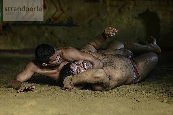 Zwei junge Männer ringen auf einem schmutzigen Boden in Indien; Varanasi  Indien