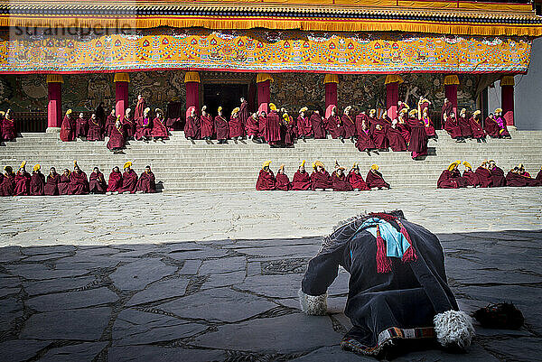 Buddhistischer Pilger  der sich vor einem Kloster mit Mönchen niederwirft; Labrang  Amdo  China