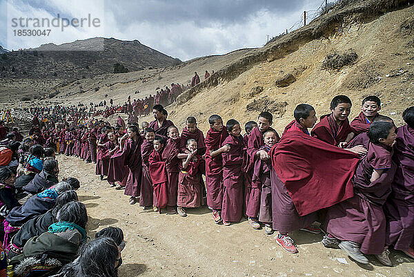 Junge buddhistische Mönche und Pilger auf einer staubigen Straße auf dem Lande; Langmusi  Amdo  China
