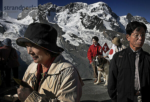 Japanische Touristen besichtigen das Matterhorn und posieren für Fotos mit den ikonischen Bernhardinerhunden in den Alpen. Rund zwei Millionen Touristen besuchen jährlich das beliebteste Reiseziel der Schweiz in der Nähe von Zermatt; die Schweiz