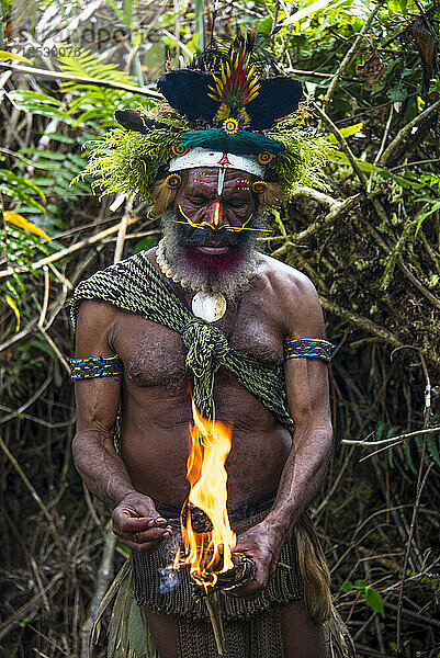 Huli-Stammesangehöriger mit Perücke und Feuer im Tari-Tal im südlichen Hochland von Papua-Neuguinea; Tigibi  südliches Hochland  Papua-Neuguinea