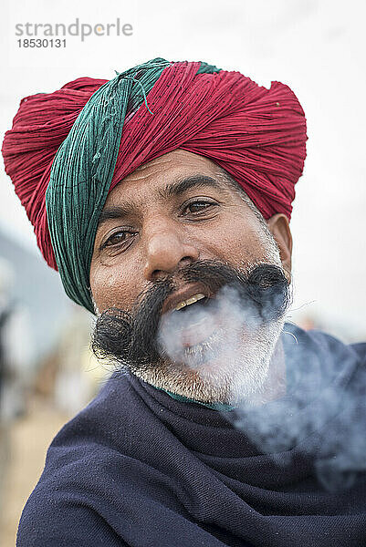 Nahaufnahme eines indischen Mannes  der Chillum-Rauch aus dem Mund bläst; Pushkar  Rajasthan  Indien