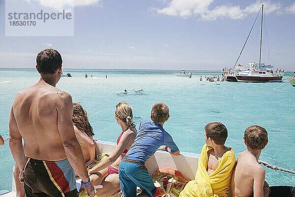 Eine Familie blickt von einem Boot aus in Richtung Stingray City  einer beliebten vorgelagerten Sandbank  auf der sich die Rochen an den Menschen gewöhnt haben  so dass dieser gefahrlos neben den Tieren schwimmen kann; Grand Cayman  Cayman Islands