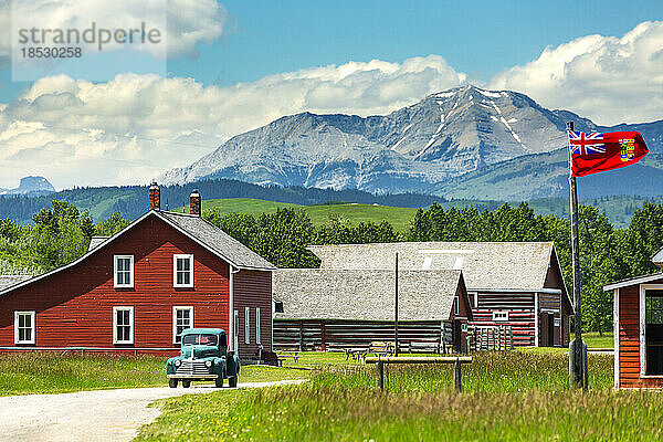 Historischer Ort mit rot gestrichenen Gebäuden  altem Lastwagen  Vorgebirge  Bergen  blauem Himmel und Wolken im Hintergrund  südlich von Longview  Alberta; Alberta  Kanada