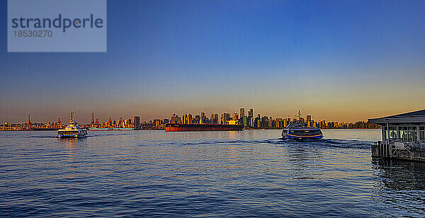 Blick auf die Skyline der Innenstadt von Vancouver in der Abenddämmerung vom Kai in North Vancouver mit Booten  die in der Bucht fahren; Vancouver  British Columbia  Kanada