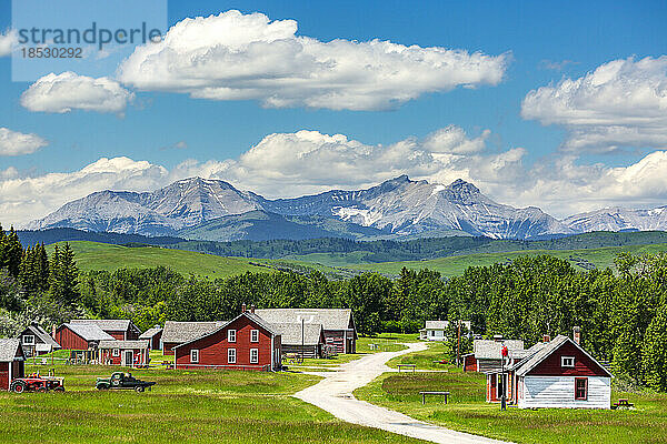 Historischer Ort mit rot gestrichenen Gebäuden  Ausläufern  Bergen  blauem Himmel und Wolken im Hintergrund  südlich von Longview  Alberta; Alberta  Kanada