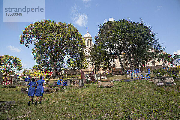 Schulmädchen in blauen Schuluniformen in der Pause auf einem Friedhof; St. John's  Antigua  Antigua und Barabuda