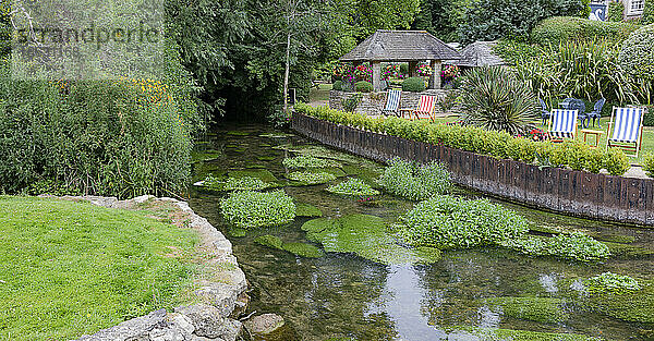 Sitzgelegenheiten am Flussufer in Gärten entlang des Flusses Coln; Bibury  Gloucestershire  England