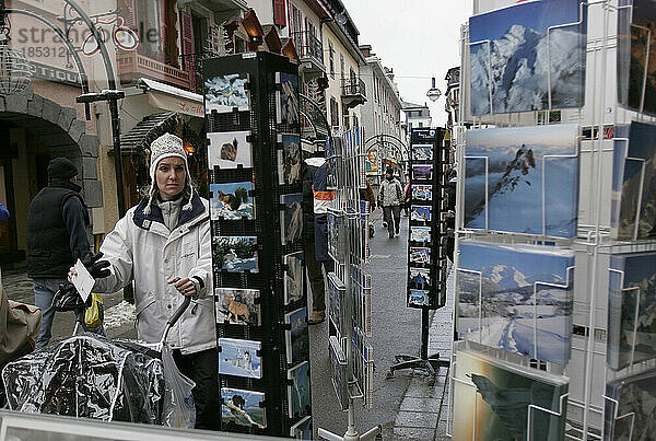 Frau stöbert in einem Geschäft für Touristenpostkarten  auf denen die Berglandschaft der Alpen und Sehenswürdigkeiten abgebildet sind  an einem Straßenstand für Touristen in Chamonix; Chamonix  Frankreich