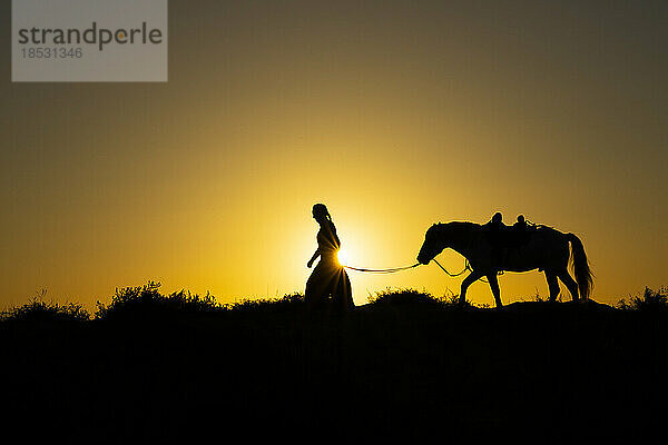 Frau führt Pferd  Silhouette bei Sonnenaufgang; Saintes-Maries-de-la-Mer  Frankreich