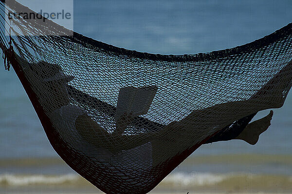 Frau liest in einer Hängematte an einem Strand im Coiba-Nationalpark; Panama