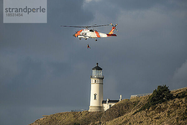 Hubschrauber der US-Küstenwache fliegt in der Nähe des Cape Disappointment North Head Lighthouse während eines Trainingseinsatzes; Ilwaco  Washington  Vereinigte Staaten von Amerika