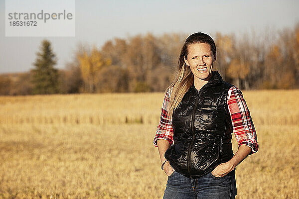 Ein Porträt einer attraktiven Bäuerin  die zur Erntezeit auf einem Feld für die Kamera posiert; Alcomdale  Alberta  Kanada
