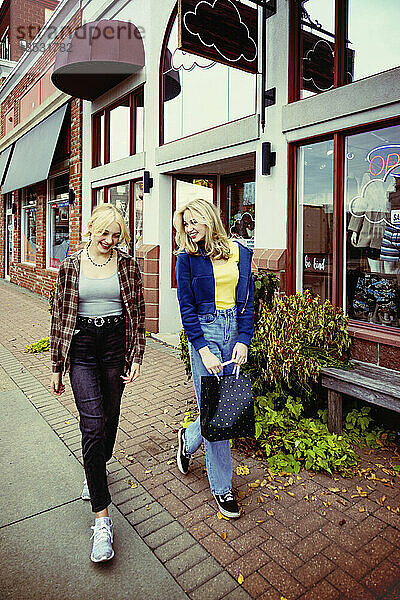 Zwei Teenager genießen einen gemeinsamen Tag beim Einkaufen und gehen an einem Herbsttag eine Straße entlang; St. Albert  Alberta  Kanada