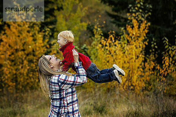 Mutter spielt im Freien mit ihrem kleinen Sohn und hebt ihn in die Luft; Edmonton  Alberta  Kanada